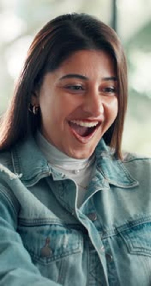 Excited Young Woman Celebrates Good News Indoors