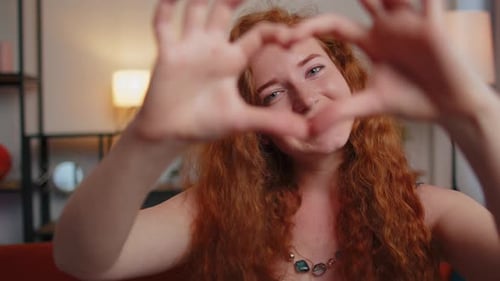 Woman Makes Heart Shape with Hands Indoors