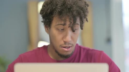 Close Up of African Man Coughing while Working on Laptop