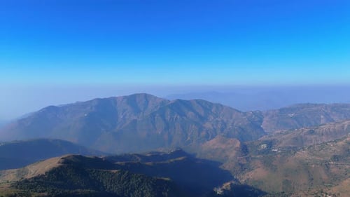 Rugged terrains and rolling hills bathed in golden sunlight create a breathtaking mountain