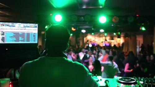 DJ Plays Music at Nightclub with Crowd Dancing