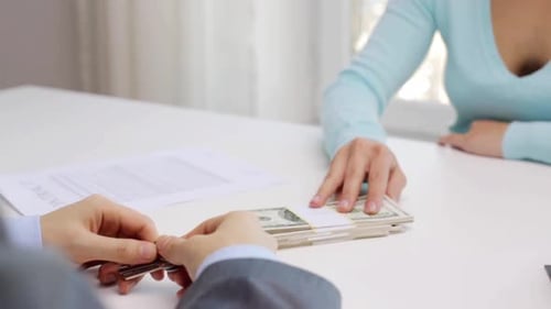 Woman makes payment to realtor and receives house keys in real estate deal