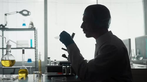 A Young Scientist in a Research Laboratory Examines a Sample on a Micropreparation Using a