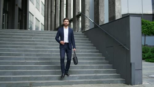 Geschäftsmann, der die Treppe eines städtischen Bürogebäudes hinuntergeht. Selbstbewusst, gutaussehend
, bärtig