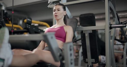 A Young Beautiful Brunette Girl in Sportswear Exercises on a Simulator in the Gym Doing Exercises