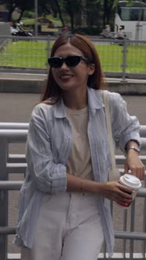 Woman Posing with Coffee Cup on an Urban Bridge