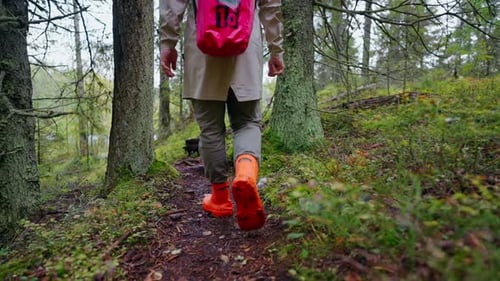 Man Traveler Walking In Forest Back View Of His Feet In Rubber Boots Stepping On Wet Ground