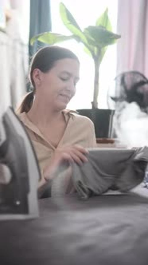 Femme repassant des vêtements dans un intérieur lumineux, routine quotidienne, tâches ménagères