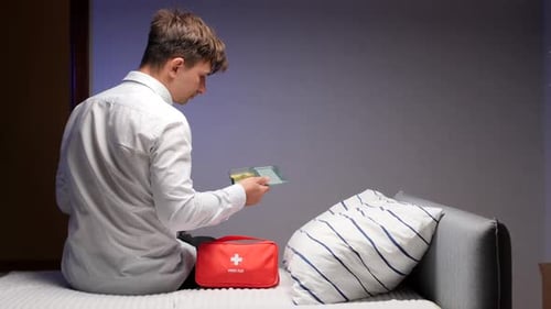 Man Takes Pills with Water on Bed