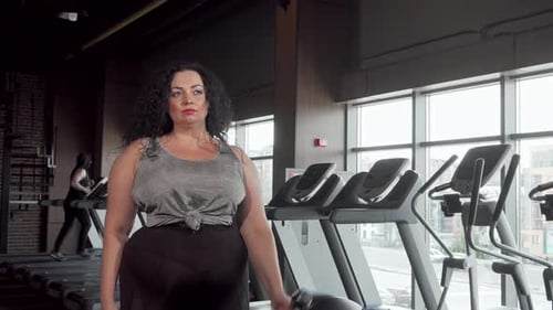 Confident Plussize Woman Lifting Dumbbells in a Modern Gym