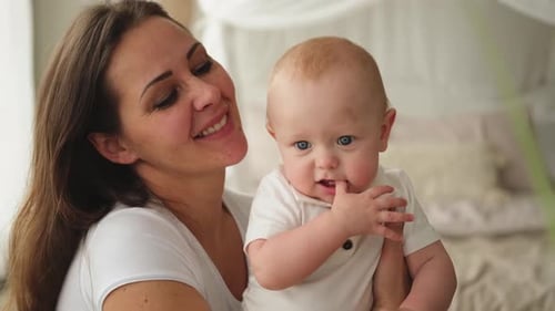 Loving Mother Holding Adorable Baby Indoors