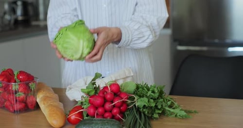 Una compradora desempaqueta los alimentos de una bolsa de embalaje ecológico y trae los alimentos de la tienda de forma ecológica