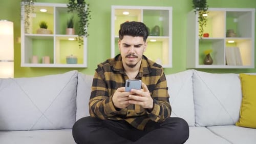 Young Man Using Smartphone on Couch Indoors