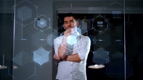Homme d'affaires utilisant une technologie de paroi de verre futuriste la nuit dans un bureau d'entreprise