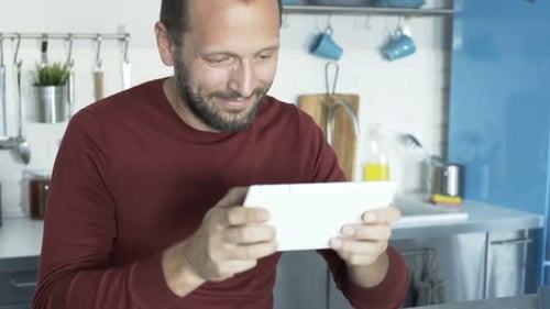 Smiling man using digital tablet in kitchen setting