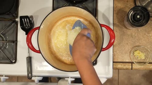Dumping diced onions into a hot pot with melted butter to sauté them for a homemade recipe - overhea
