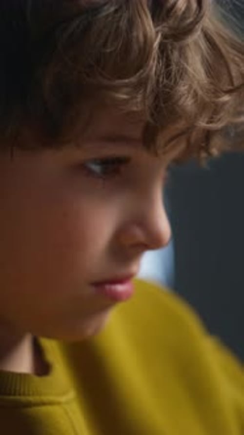 Closeup of a Child Focused on Writing with a Pencil on Paper and Wearing Large Headphones Engaging