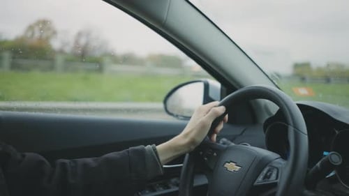 Driver's Hand On The Steering Wheel Of A Chevrolet Car - Driving On The Road - handheld shot