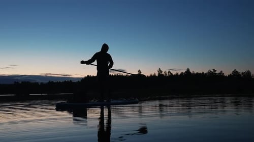 Stand Up Paddle Boarding or Standup Paddleboarding on Quiet Lake at Sunrise
