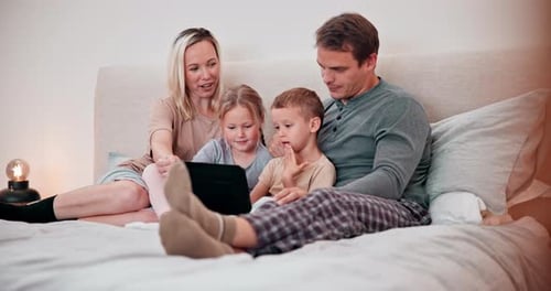 Family Watching Tablet Together on Bed at Home