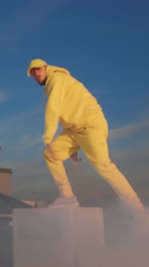 Urban Dawn Stance Man in Bright Yellow Outfit Poses Confidently on Rooftop During Sunrise with