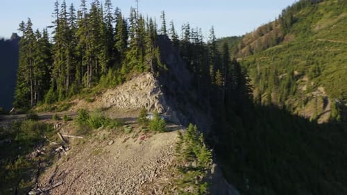 Large pick up truck stands close to edge of steep cliff at rocky mountain summit
