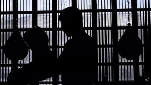 Silhouette eines muskulösen Mannes, der vor dem Training Boxhandschuhe anzieht