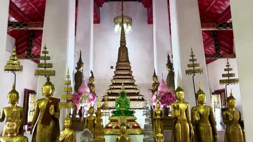 The inside of a Buddhist temple in Thailand. There is a shrine with several golden figures. The came