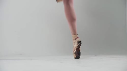 Young Woman Ballerina Walking on Pointe Shoes in White Studio