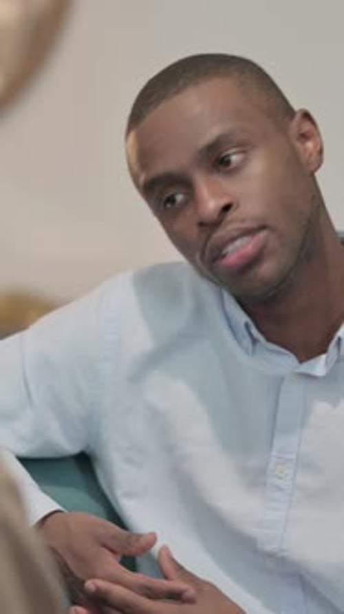 Couple ayant une conversation sérieuse assis sur un canapé, vue arrière, vidéo verticale