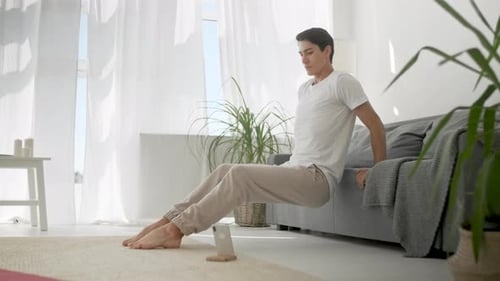 Young Man Doing Tricep Dips on Sofa at Home