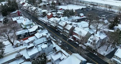 Line of houses along street. Small town in USA. American winter snow scene. Tilt up reveal above roa