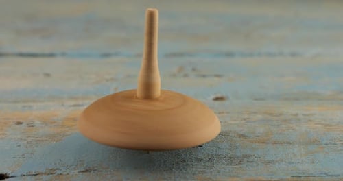 Wooden Toy Top Spinning on Painted Blue Table