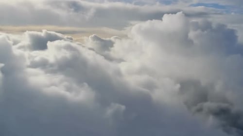 Aerial view of soft white fluffy clouds moving past the came