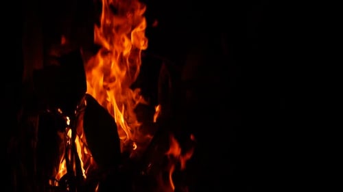 Blazing fire burning vigorously behind substance in the dark