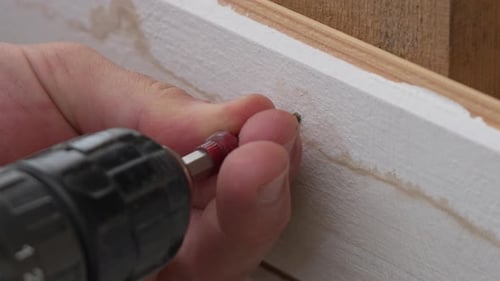 A Man Hands Using a Power Tool Fastens a Board with a Screw Slow Motion