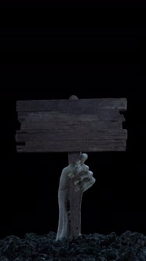 A Zombie Hand with a Wooden Sign Crawls Out of the Ground with Alpha Channel