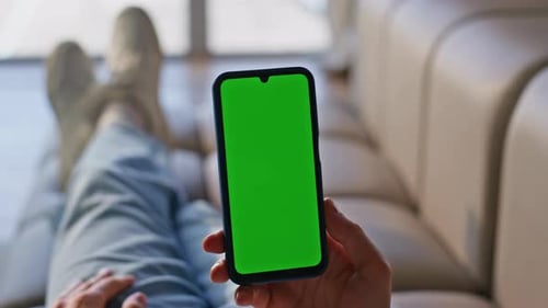 Person uses phone with green screen on couch