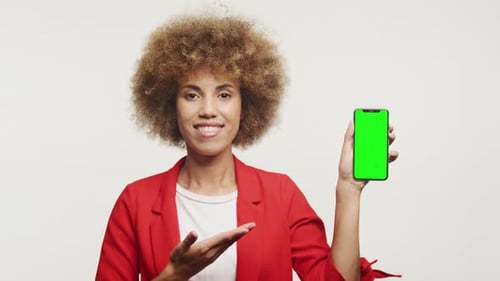 Smiling Woman Presenting Smartphone with Green Screen
