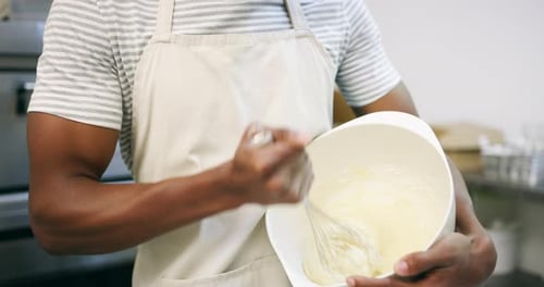 4k video footage of a young male baker mixing ingredients in a bowl at a bakery