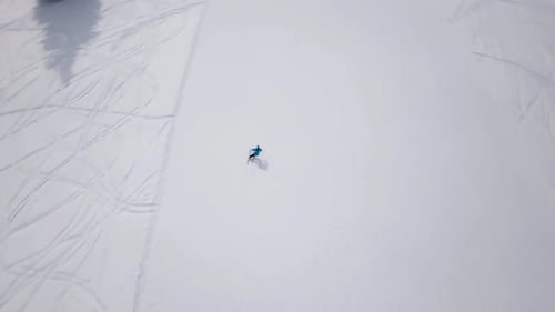 Luftaufnahme des Skigebiets an sonnigen Bergen mit Pinienwald. Skifahrer fahren an Liften auf der Schneehänge hinunter.
Gewinnen