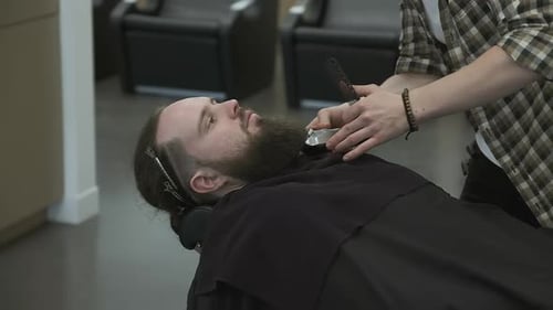 Barber Trimming Beard of Relaxed Adult Man