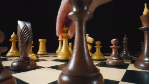 Spieler klopft schwarze Königin mit weißer Hand in einer Schachpartie