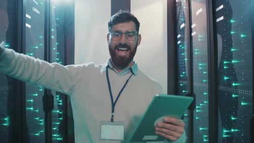 Excited man with tablet dancing in server room
