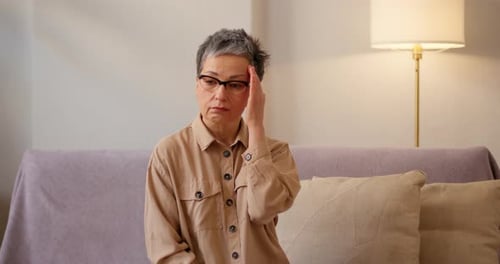Woman with Headache Rubbing Temple on Sofa
