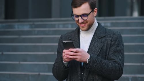 Man Smiles Using Phone Outside Urban Building
