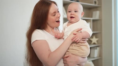Loving Mother Holding Adorable Baby Indoors
