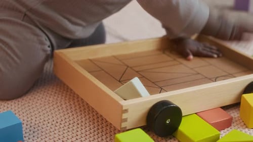 Close-up of African American Toddler Playing with Wooden Toy on Carpeted Floor