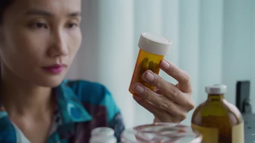 Adult Examining Prescription Medicine Bottle Indoors