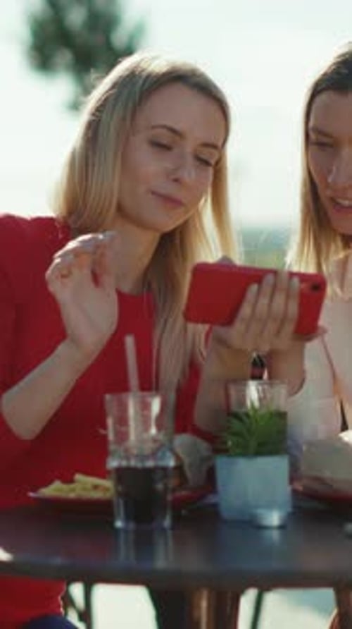 Young adults sharing smartphone over lunch at cafe